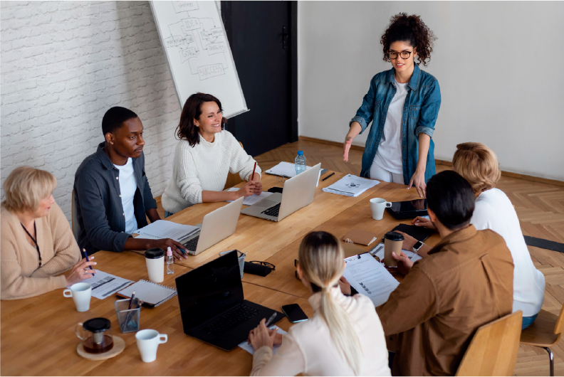 Grupo em torno de uma mesa com notebooks conversando