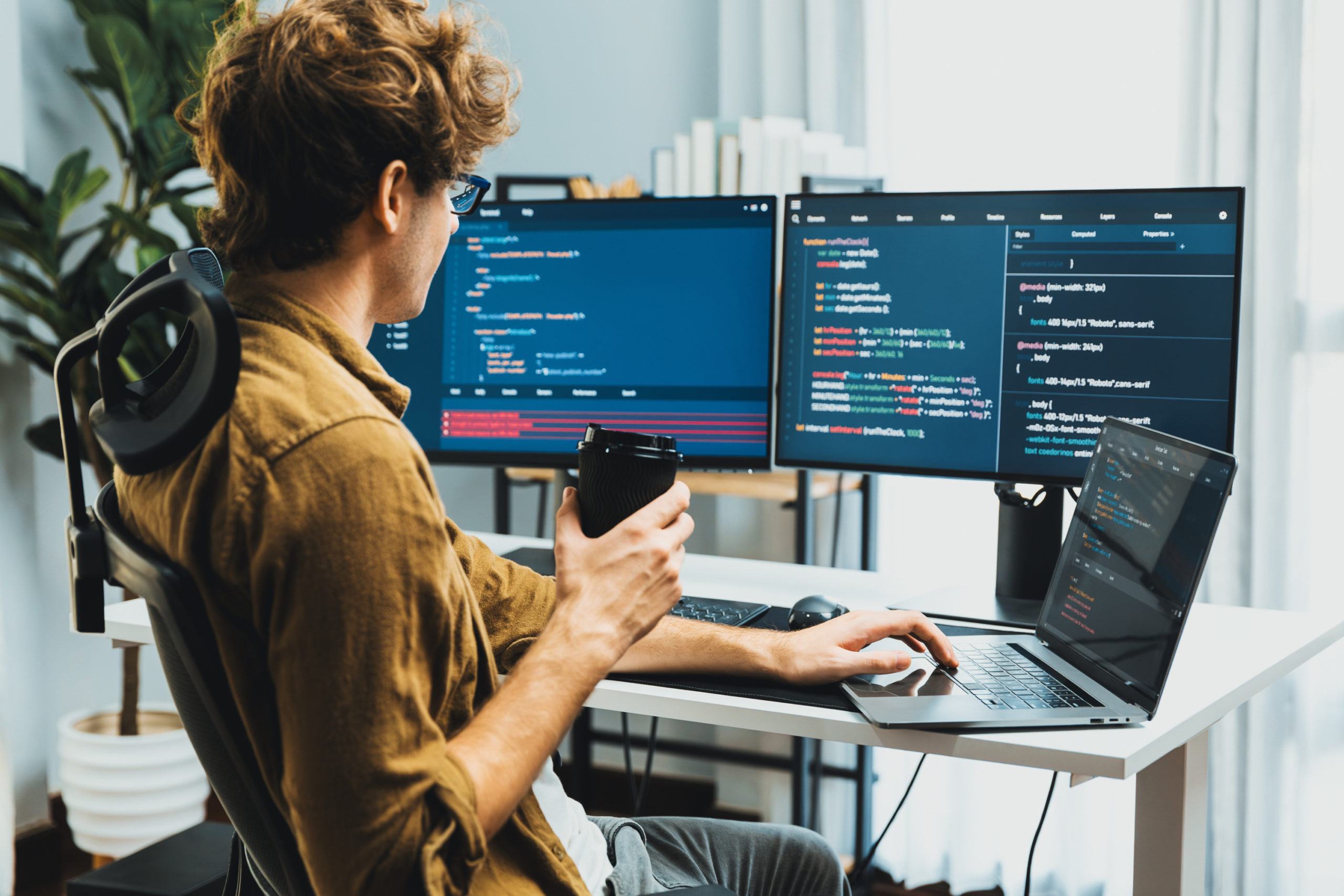 IT developer holding coffee cup with looking online software on pc. Gusher.